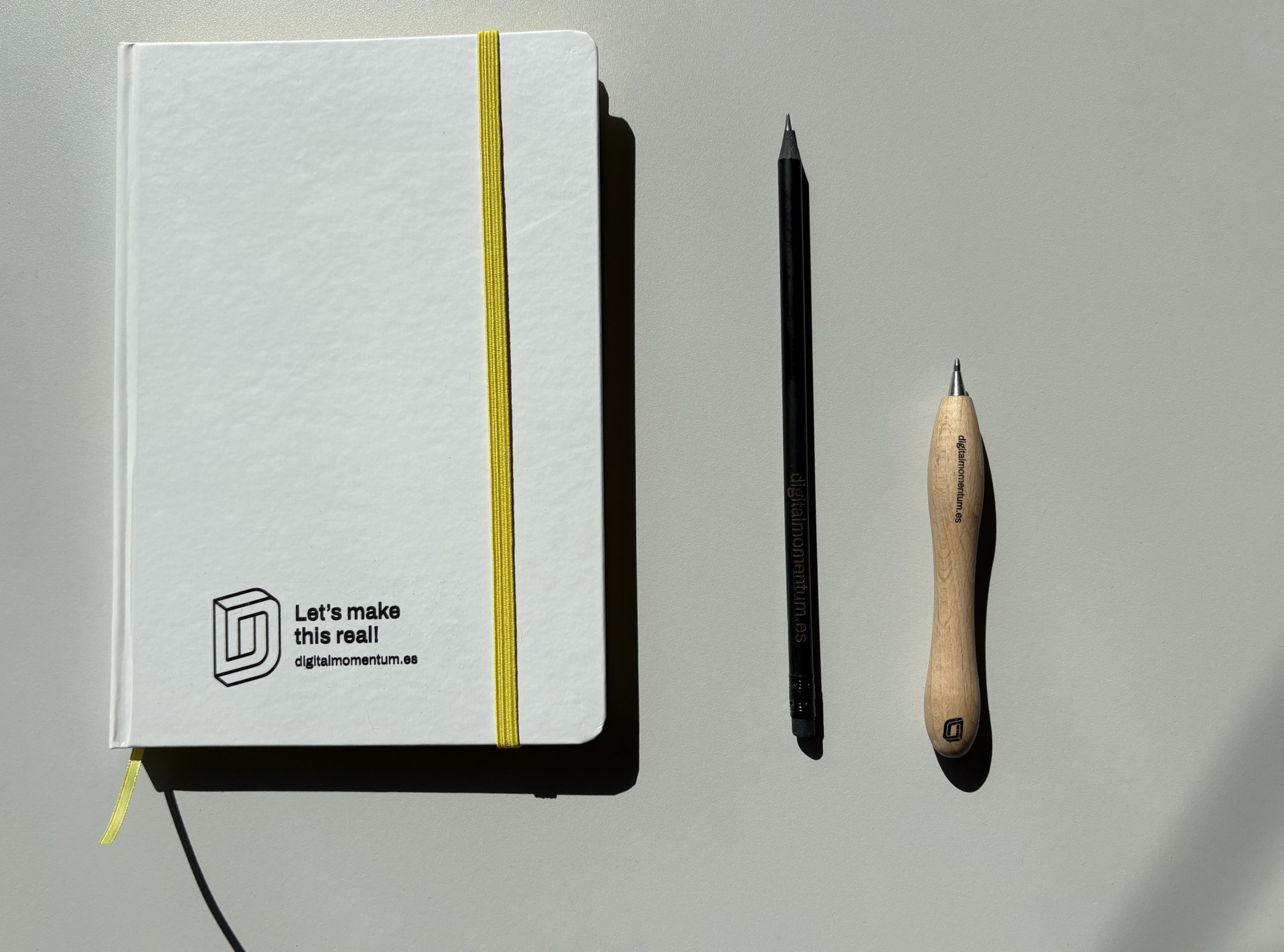 Papelería corporativa de Digital Momentum: libreta, lápiz y bolígrafo